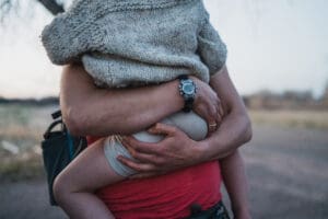 Close-up of parent holding young child wrapped in a sweater, showing quiet comfort and connection