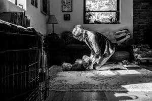 Mother and child playing on a rug in their living room, illuminated by natural morning light