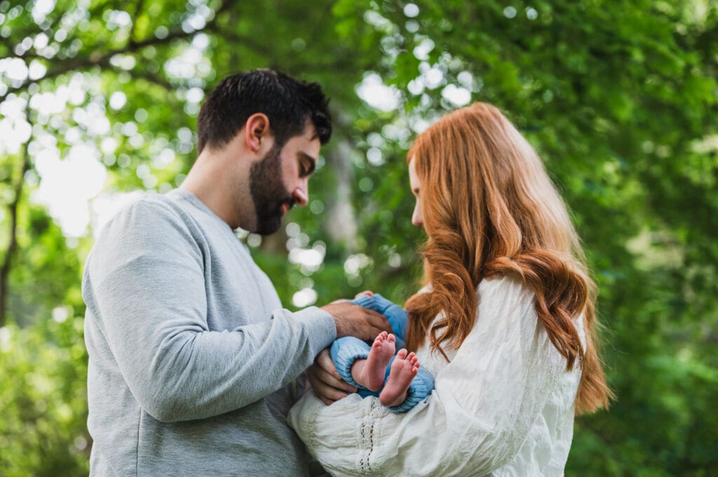 Parents holding newborn baby with tender connection outdoors