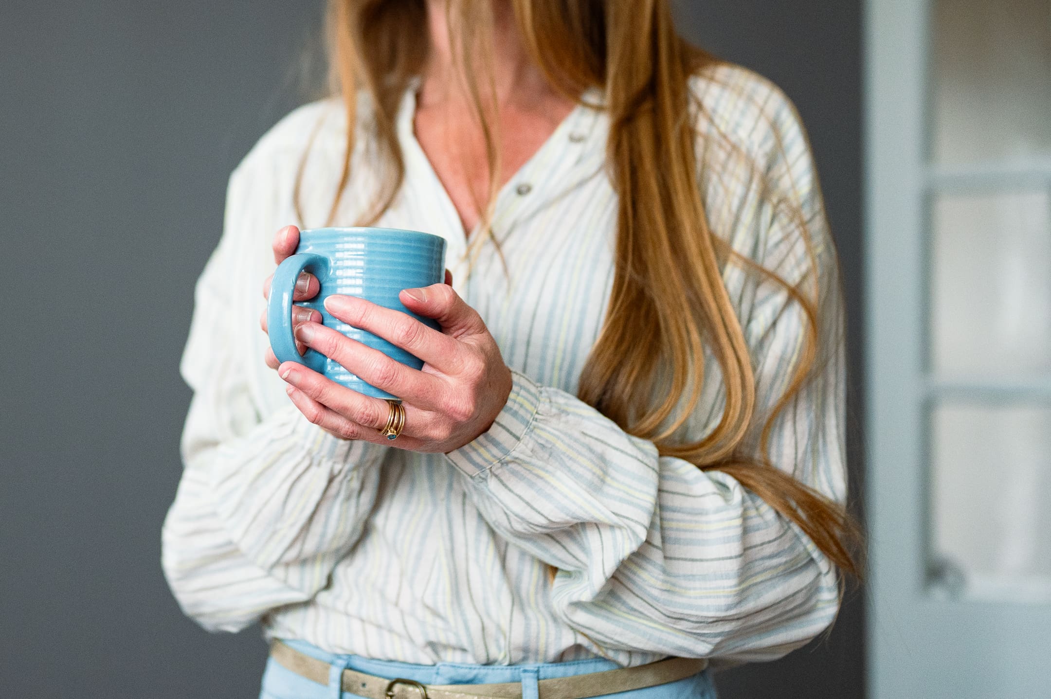 Close-up of a woman holding a blue ceramic mug during a Big Talk portrait session