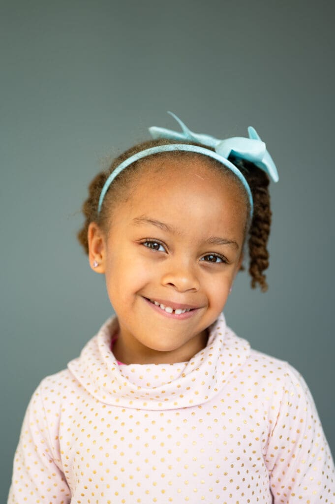 Child with headband smiling during a simple portrait session