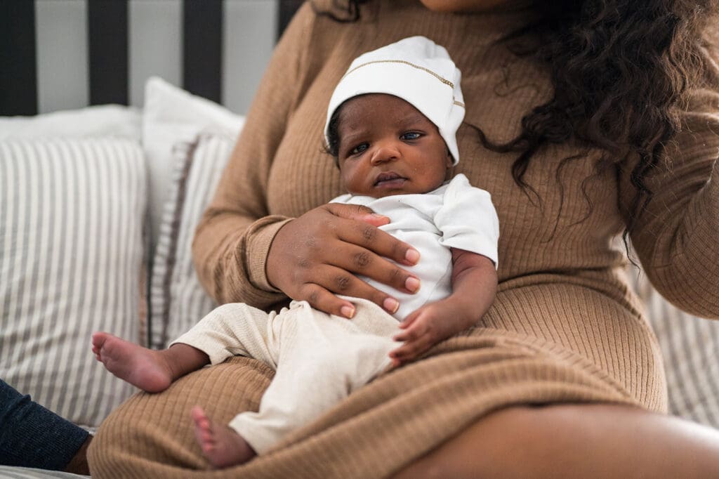 Newborn baby lying on mother’s lap during photo session