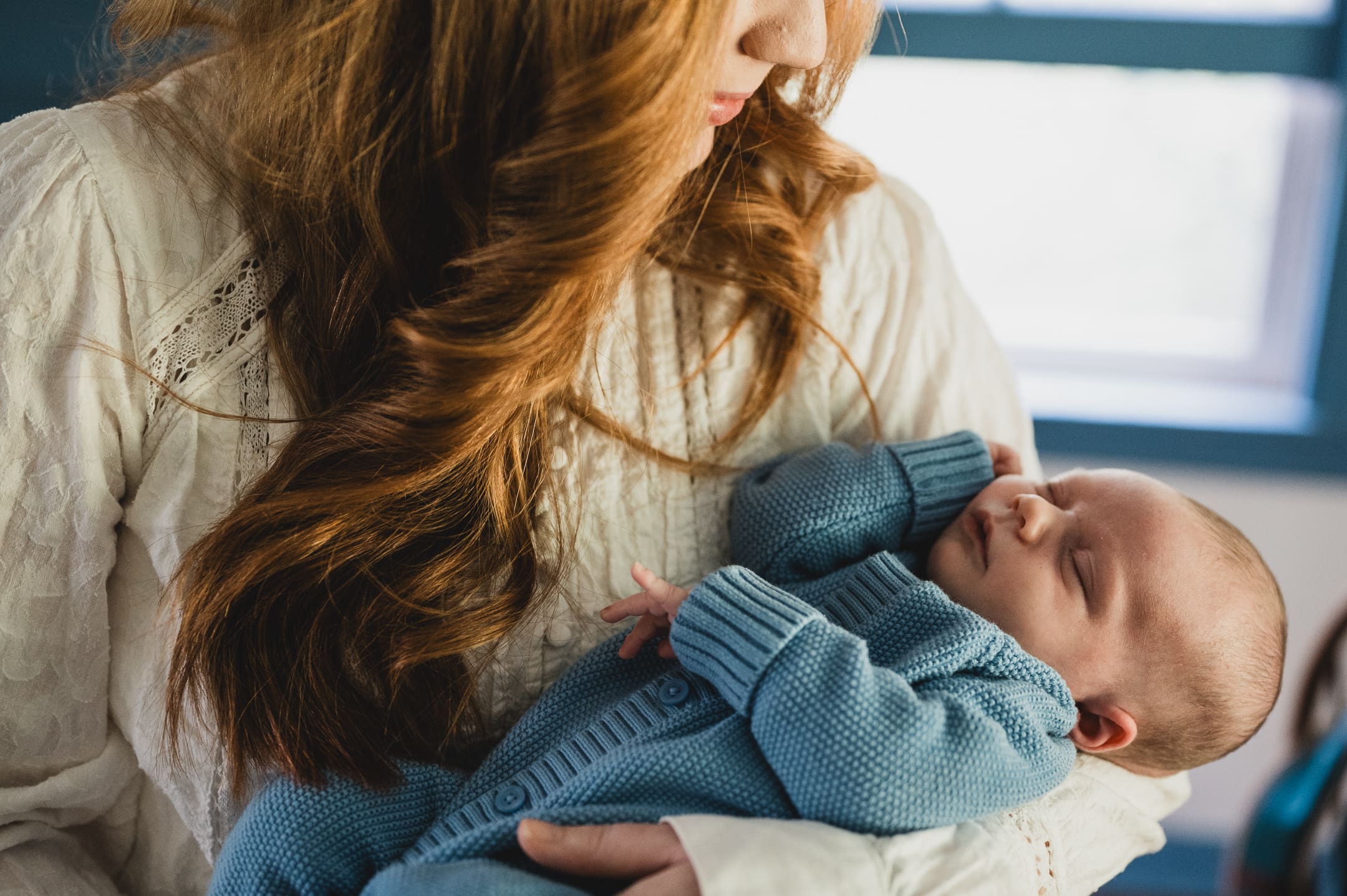 Mother holding her newborn dressed in a blue sweater