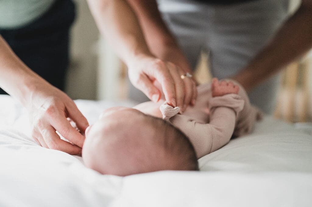 Parents placing their newborn into a crib in a cozy, light-filled nursery