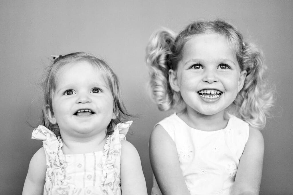 Two young sisters smiling together in black and white portrait