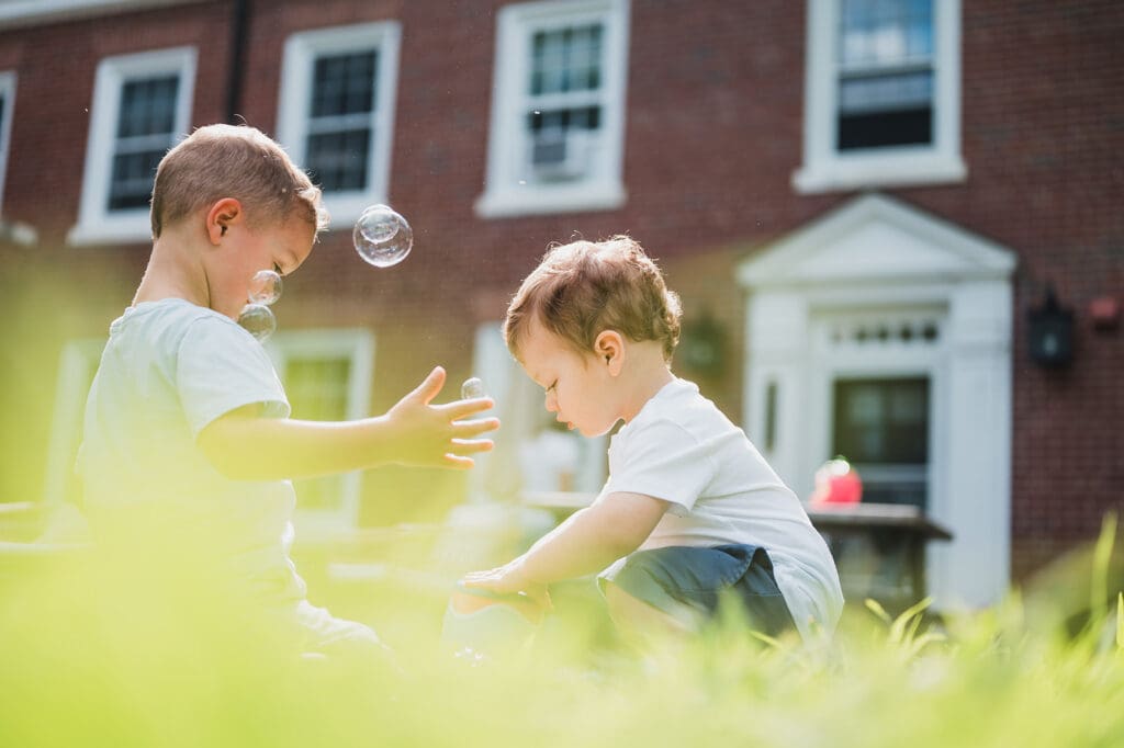 Young siblings playing with bubbles in the backyard during a family photography session