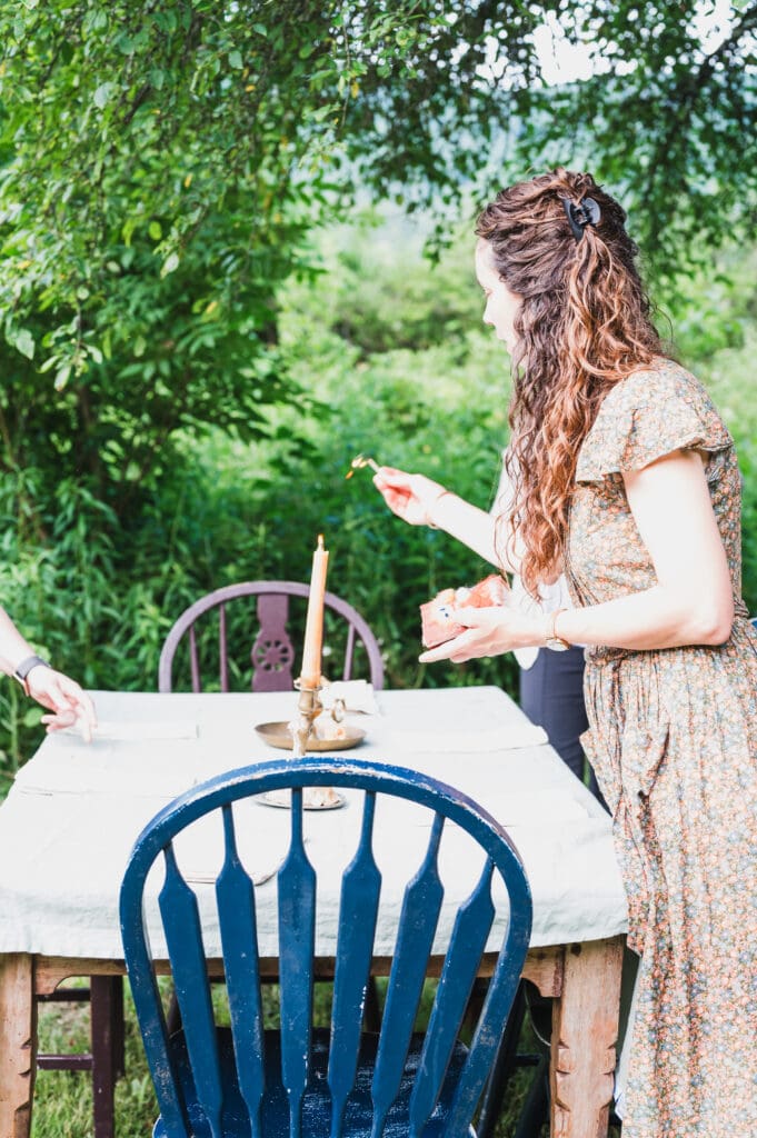 Woman placing food on an outdoor table under a tree