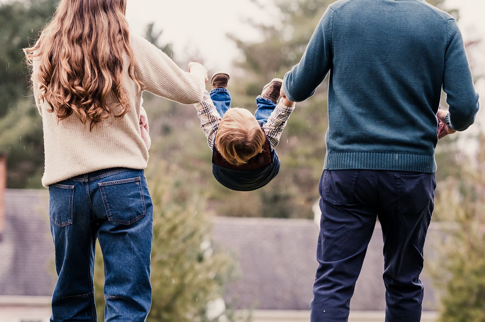 parents swinging child between them during a relaxed family moment featured in a blog about how to choose a family photographer