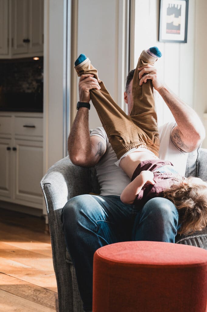 parent playfully holding child upside down during a documentary family photography session