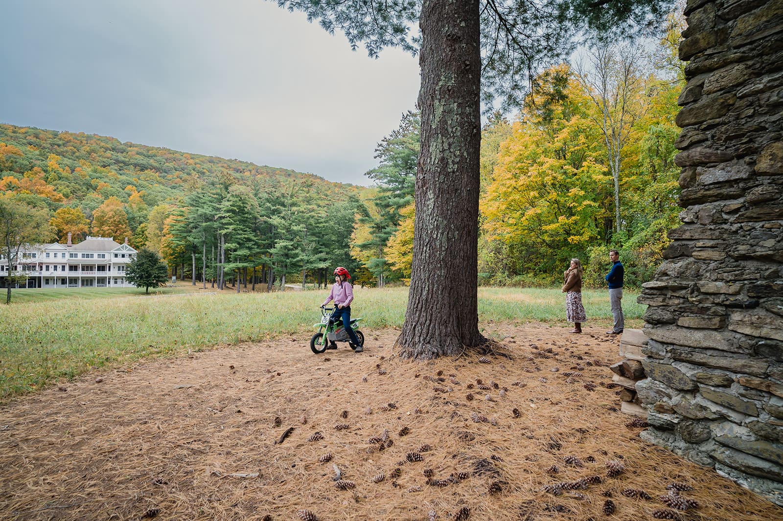 A child riding a balance bike while parents watch during a lifestyle family photography session outdoors