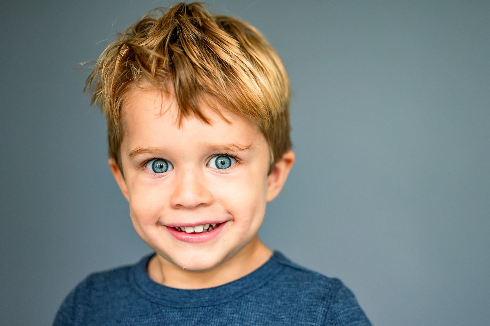 Elementary school portrait photography in natural light featuring smiling young boy on gray background