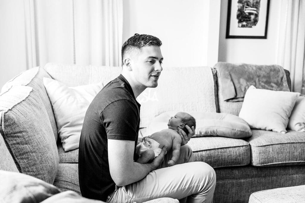 father holding newborn on couch during in home newborn photography session