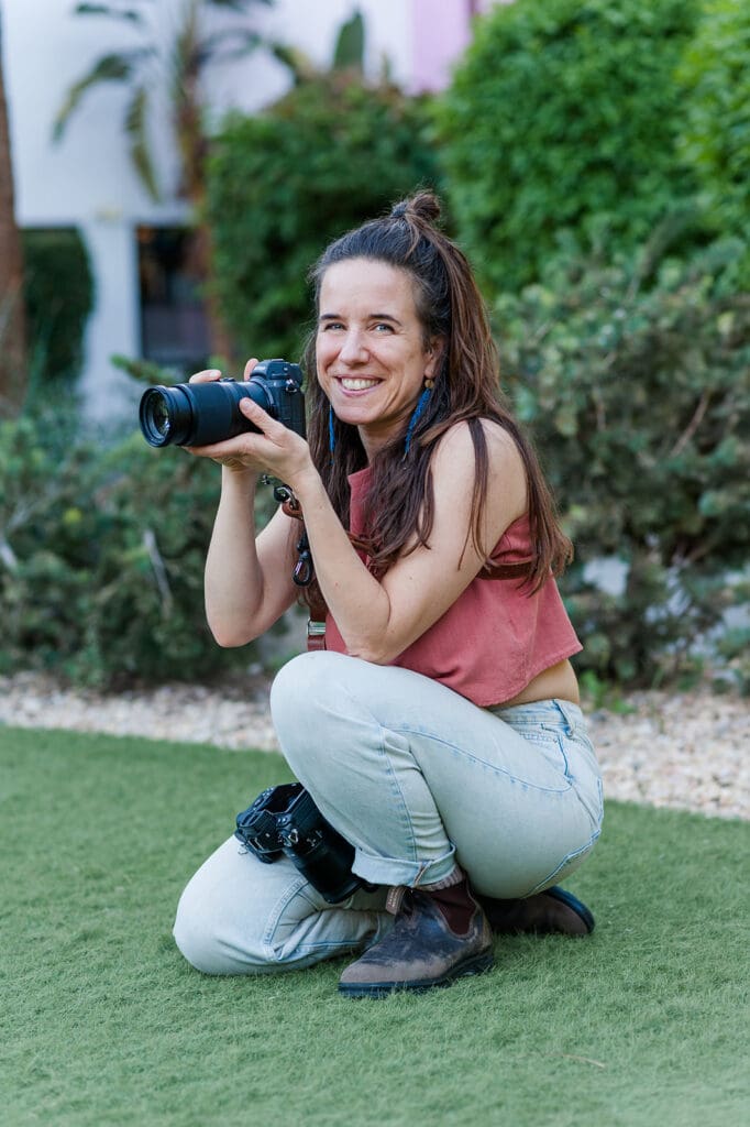 portrait of newborn photographer crouching and smiling about to take a photo outdoors