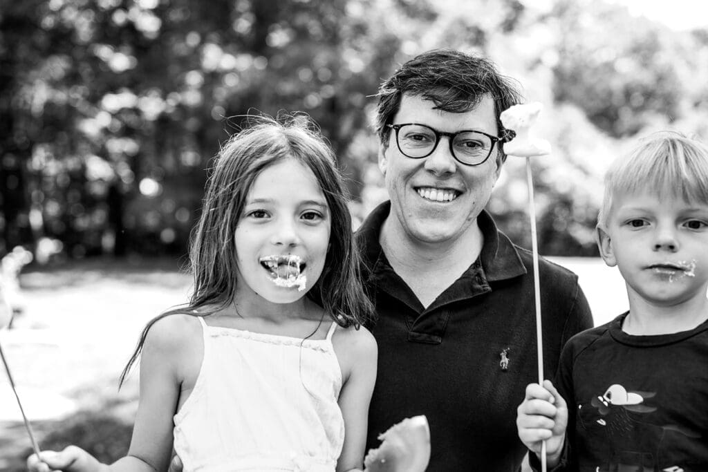 Father smiling with his two children outdoors during a documentary family photography session
