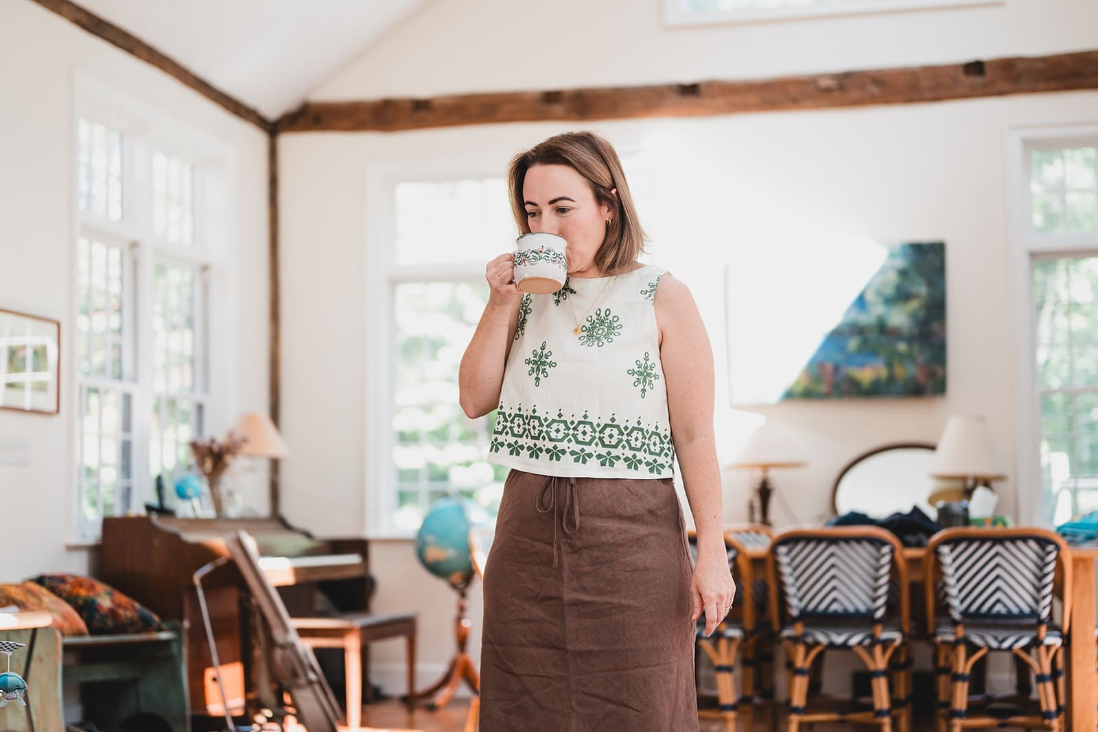 Woman drinking coffee in a sunlit doorway during a documentary family photography session