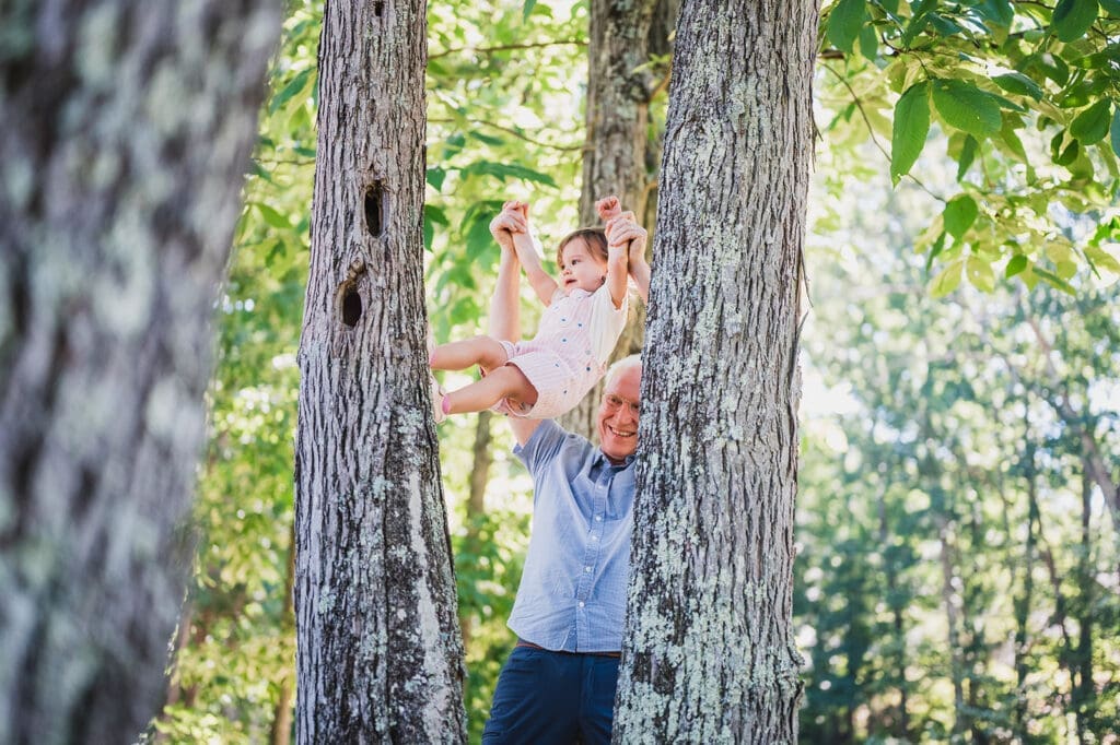 grandfather lifting grandchild between trees during Hudson Valley family vacation session