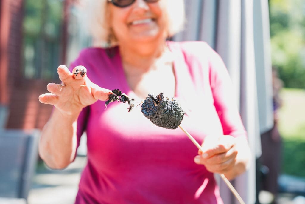 Grandmother laughing while holding a burnt marshmallow on a stick outdoors